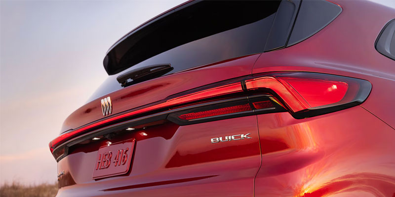A close-up of the rear end of a red Buick SUV, highlighting the sleek taillights and the "BUICK" badge